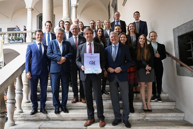 Landesrechnungshofdirektor Günter Bauer mit der Urkunde des CAF-Gütesiegels, Landeshauptmann Peter Kaiser, Vizekanzler Werner Kogler und dem gesamten Team des Landesrechnungshofs auf der Außentreppe im Landhaushof in Klagenfurt.