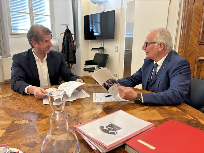 Der Landesrechnungshofdirektor und der Landtagspräsident sitzen in einem Büro an einem großen Tisch und blättern gemeinsam den Tätigkeitsbericht 2023 des Landesrechnungshofs durch.